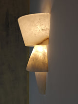 Wall-mounted light fixture with textured design on a plain wall.