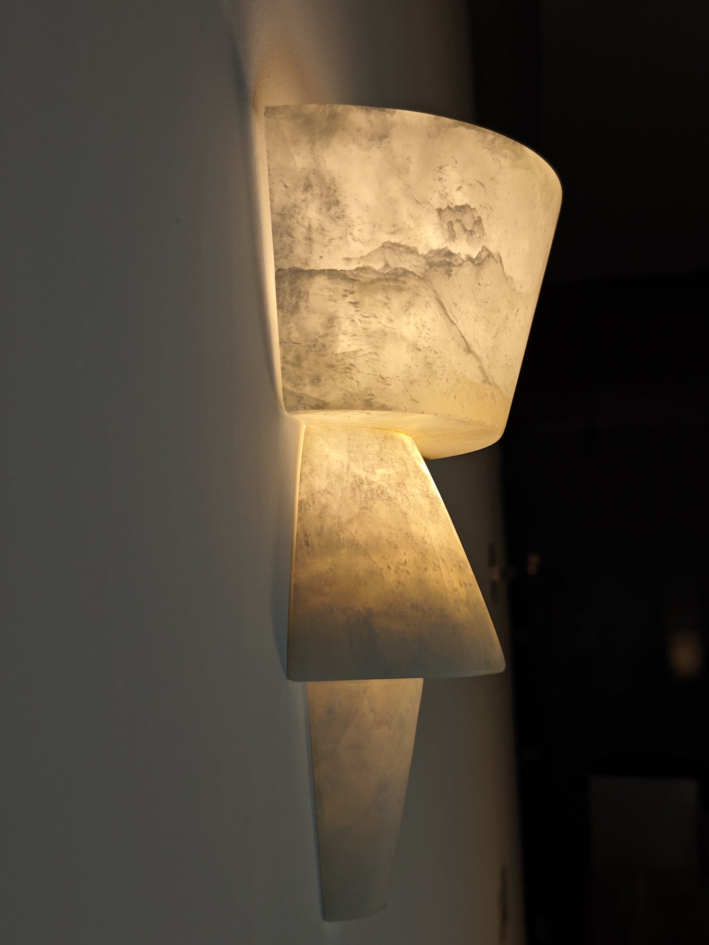 Decorative wall sconce with a textured surface on a dark background