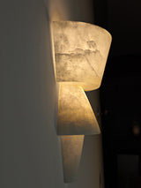 Decorative wall sconce with a textured surface on a dark background